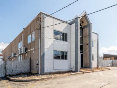 Exterior view of a 6,000 sq. ft. industrial building with a large gravel lot in front, suitable for parking or storage.
